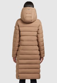 Pitkä beige puffatakkia, jossa on vaakaommelkuvio, kiinnitetty huppu ja joustavat hihansuut. Sileä pinta, jossa on minimaalista somistusta.