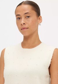 Witte mouwloze top met een ronde halslijn, met een zachte, gebreide textuur en kleine, gelijkmatig verdeelde, decoratieve parelaccenten.