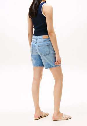 Shorts en denim de couleur bleu clair avec une coupe décontractée, un design à cinq poches et une étiquette en cuir marron avec logo à l'arrière de la taille.