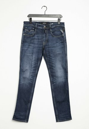 Dark blue denim jeans with a straight leg design. Features subtle fading, standard pockets, and stitching detail. Hangs from a black hanger.