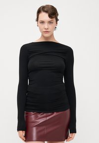 Černý dlouhý rukáv top s nařasenou texturou, lodičkovým výstřihem a slim fit. Vybavené burgundskou mini sukní z umělé kůže.