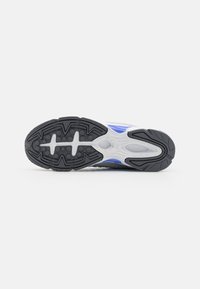 Talpa de sneaker albă și gri, cu un outsole negru texturat din cauciuc, cu accente albastre și un design în valuri. 