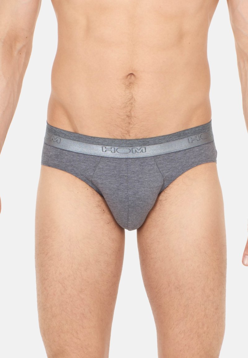 Graue Baumwollunterhose mit einem gefütterten Gummibund, auf dem der Markenname "HOM" in fetten Buchstaben steht. Der Stoff wirkt glatt und eng anliegend.
