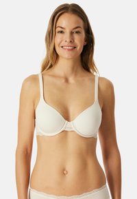 Reggiseno imbottito beige con tessuto liscio, spalline regolabili e bordo in pizzo lungo la fascia. Forma classica adatta per l'uso quotidiano.