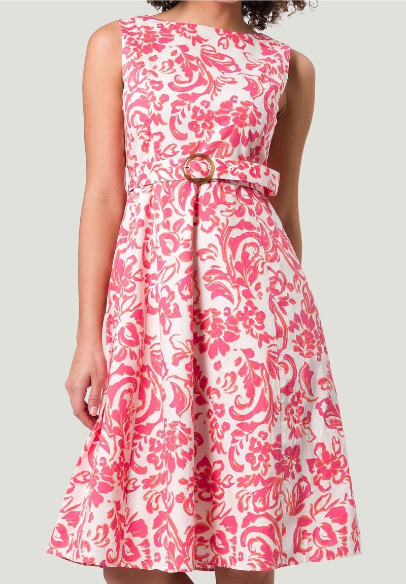 Blumenmusterkleid aus pinkem und weißem Stoff, ärmelloses Design mit tailliertem Schnitt und einem Gürtel mit runder Schnalle. Ausgestellter Rock mit Falten.