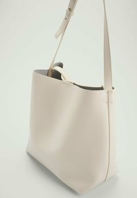 Beige tote bag met een gladde leren textuur, rechthoekige vorm, verstelbare schouderriem en minimalistisch design.