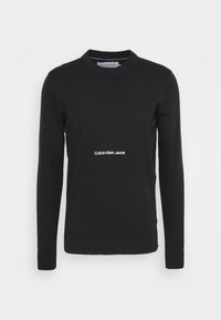 Svart bomullströja med långa ärmar, rund hals och ribbade muddar. Har vit "Calvin Klein Jeans"-logotyp på framsidan. Mjuk textur.