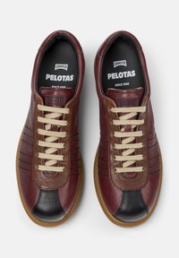 Brown and burgundy sneakers with tan laces and a black toe cap, featuring "Camper Pelotas" branding on the insoles.