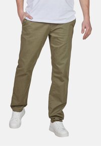 Khaki katoenen broeken met een recht-gesneden pasvorm, voorzien van zijzakken, gedragen met witte sneakers. Gladde textuur, casual ontwerp.