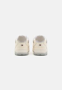 Sneaker beige con tomaia in pelle liscia, colletto imbottito, dettagli grigi e suole testurizzate. Toppa con logo visibile sul tallone.