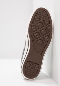 Graue Leinensneaker mit einer weißen Gummisohle, die auf der Unterseite ein rautenförmiges Profil und ein silbernes Metall-Ösen-Detail aufweist.