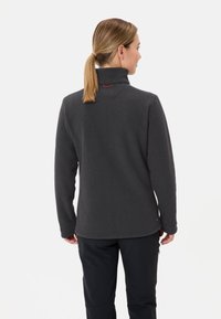 Giacca in pile grigio scuro con colletto alto, maniche lunghe e superficie liscia. Presenta un discreto accento rosso sul retro del collo.