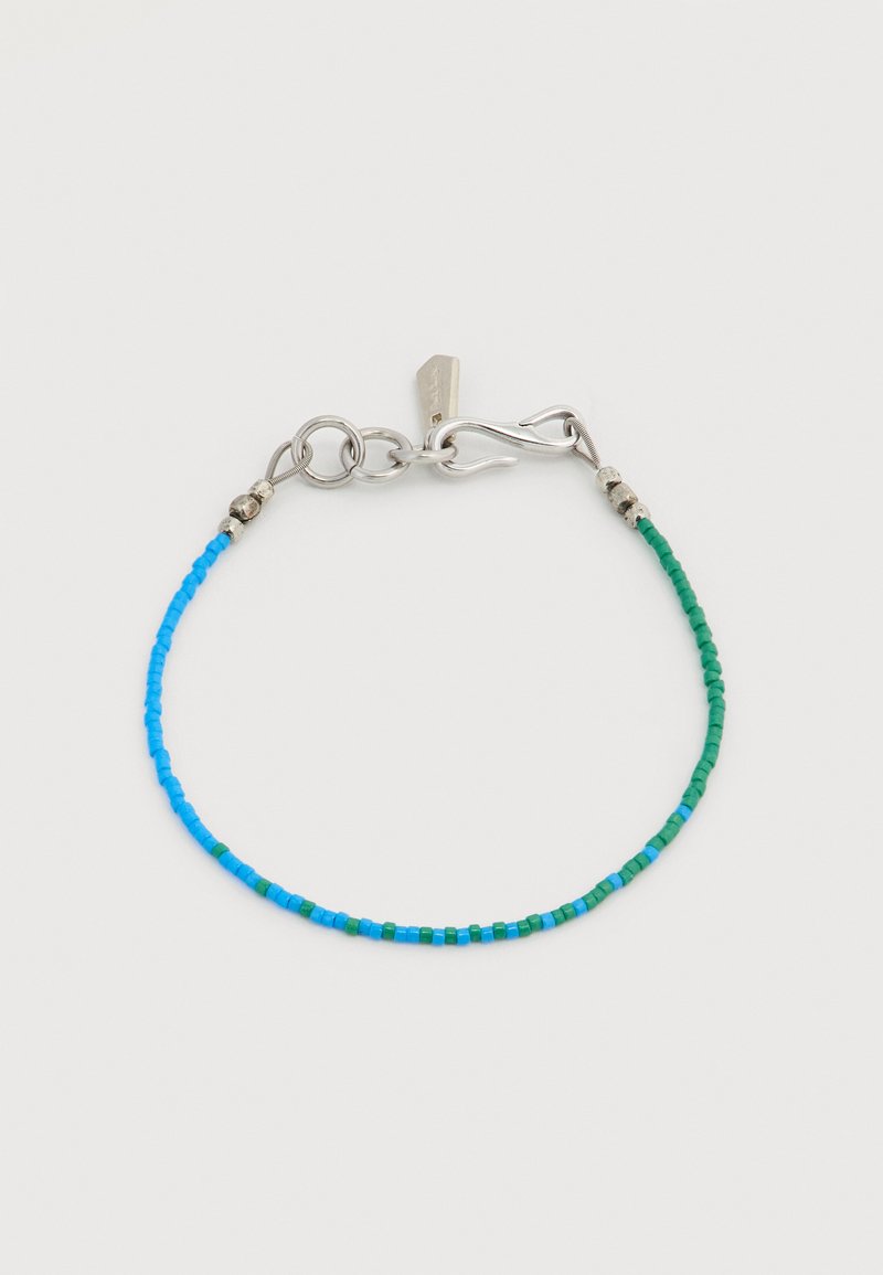 Λεπτό βραχιόλι με μικρές μπλε και πράσινες χάντρες και ασημένιο κούμπωμα με γάντζο σε απλό λευκό φόντο.