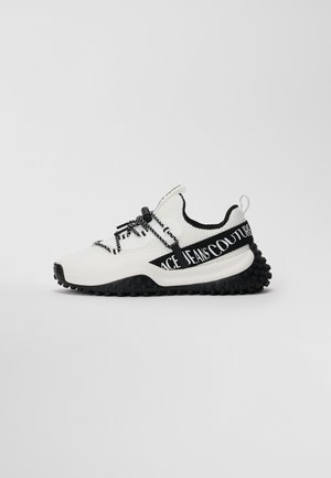 Weiße und schwarze Low-Top-Sneaker mit strukturiertem Sohlen, schwarzen Schnürsenkeln und "Versace Jeans Couture"-Text auf dem seitlichen Riemen.