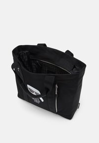 Zwarte tote bag met afgeronde hoeken, voorzien van een witte grafische afbeelding. Inclusief dubbele hengsels en een met rits afsluitbaar binnenvak.