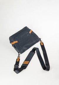 Dark gray crossbody bag with adjustable black strap and tan leather accent patches on strap and bag corners.