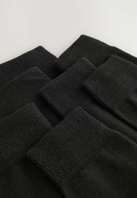 Sosete negre, cu textură ribbed, stivuite, arătând un model de tricot texturat și detalii cu manșetă largă. Materialul pare moale și flexibil.