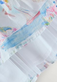 Tissu blanc avec une scène peinte en bord de mer mettant en scène des voiliers, des palmiers et de l'eau, combiné avec un matériau en maille blanche transparente.