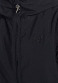 Svart huva jacka med en mjuk textur, dragkedjestängning och en subtil präglad logotyp på vänster bröst. Hög krage design.