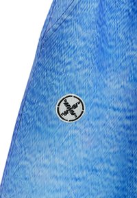 Tejido de mezclilla azul con un patrón texturizado. Presenta un logotipo bordado redondo en blanco y negro en una costura lateral.