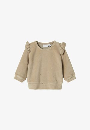 Beżowy polarowy sweter z falbaniastymi akcentami na ramionach, teksturowanymi kropkami i elastycznymi mankietami. Posiada okrągły dekolt i prążkowany dół.
