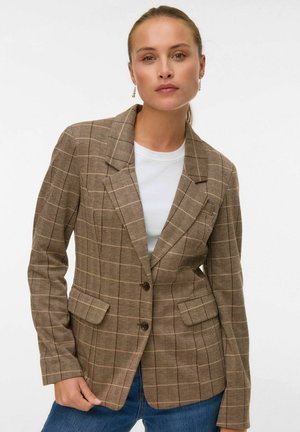 Brun ternet blazer lavet af tekstureret stof med en slagkrave, frontknapper og to sidelommer. Båret over en hvid bluse.