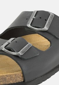 Sandalo in pelle nera con doppi cinturini regolabili in argento, sottopiede in sughero e suola in gomma testurizzata.
