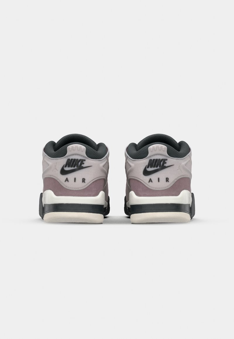 Sneakers Nike z gładką szarością na cholewce i różowymi akcentami. Posiadają wyściełany kołnierz, czarne sznurowadła oraz białą podeszwę środkową z teksturowaną podeszwą zewnętrzną.