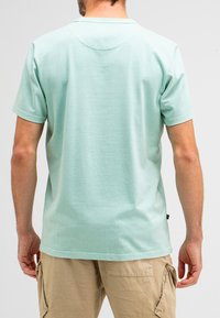 Light mint green t-shirt made of soft fabric, featuring a crew neckline and short sleeves, with a straight hem and minimal stitching details.