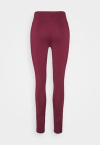 Leggings burdeos con una cintura alta, tela suave y un diseño ajustado con tobillos entallados. Sin patrones visibles ni elementos de hardware.
