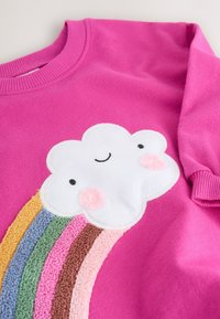 Pull rose vif avec un patch nuage blanc souriant et un arc-en-ciel texturé en jaune, bleu, vert, rose, marron et pêche.