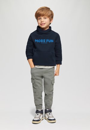 Navy blauwe sweatshirt met de tekst "MEER PLEZIER GRAAG", grijze cargobroek en sneakers met hoge schacht en gemusterde accenten. Casual outfit voor kinderen.