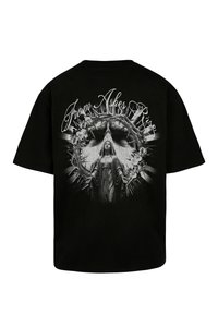 Juoda marškinėliai su pilkų atspalvių grafika, vaizduojančia apsiaustą dėvinčią figūrą, laikantį erškėčių karūną, puoštą gėlėmis, viršuje užrašyta „Iš pelenų pakyla“.