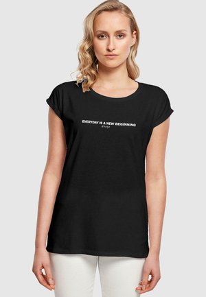 Schwarzes T-Shirt mit kurzen, gerollten Ärmeln und rundem Halsausschnitt. Text "JEDER TAG IST EIN NEUER BEGINN #hoffnung" in Weiß über die Brust. Weicher Stoff.