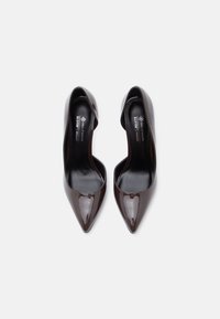 Καφέ γυαλιστερά δερμάτινα ψηλοτάκουνα παπούτσια με μυτερές μύτες και ανοιχτές πλευρές, με λεία υφή και ελάχιστη σήμανση στο εσωτερικό πέλμα.