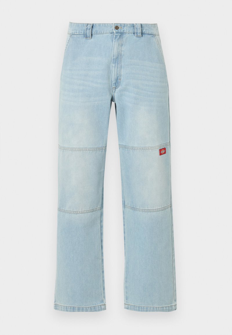 Hellblaue Jeans mit weitem Bein, Kniepaneel-Details und einem kleinen roten rechteckigen Logo-Patch am rechten Oberschenkel.