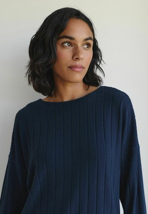 Navy blue ribbed knit top with a wide boat neck, relaxed fit, and long sleeves. The texture is soft, with vertical stripes for added detail.