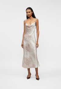 Μεσοφόρεμα από μετάξι με ρυθμιστές, σε ανοιχτό μπεζ χρώμα και διακριτική υφή με σχέδιο ζώων, ρέων σιλουέτα και ουδέτερο τόνο.