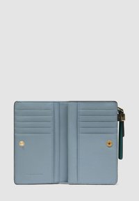 Portafoglio in pelle azzurro chiaro aperto che mostra molteplici scomparti per carte, due tasche con bottone a pressione e un portachiavi verde attaccato sul lato.