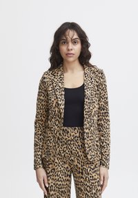 Blazer in stampa leopardata realizzato in tessuto leggero, con chiusura a un bottone, bavero a punte e due tasche frontali. Abbinato a pantaloni coordinati.