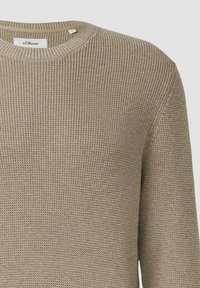 Beige gebreide trui met een ronde hals en ribbelstructuur. Eenvoudig design met een label aan de hals.