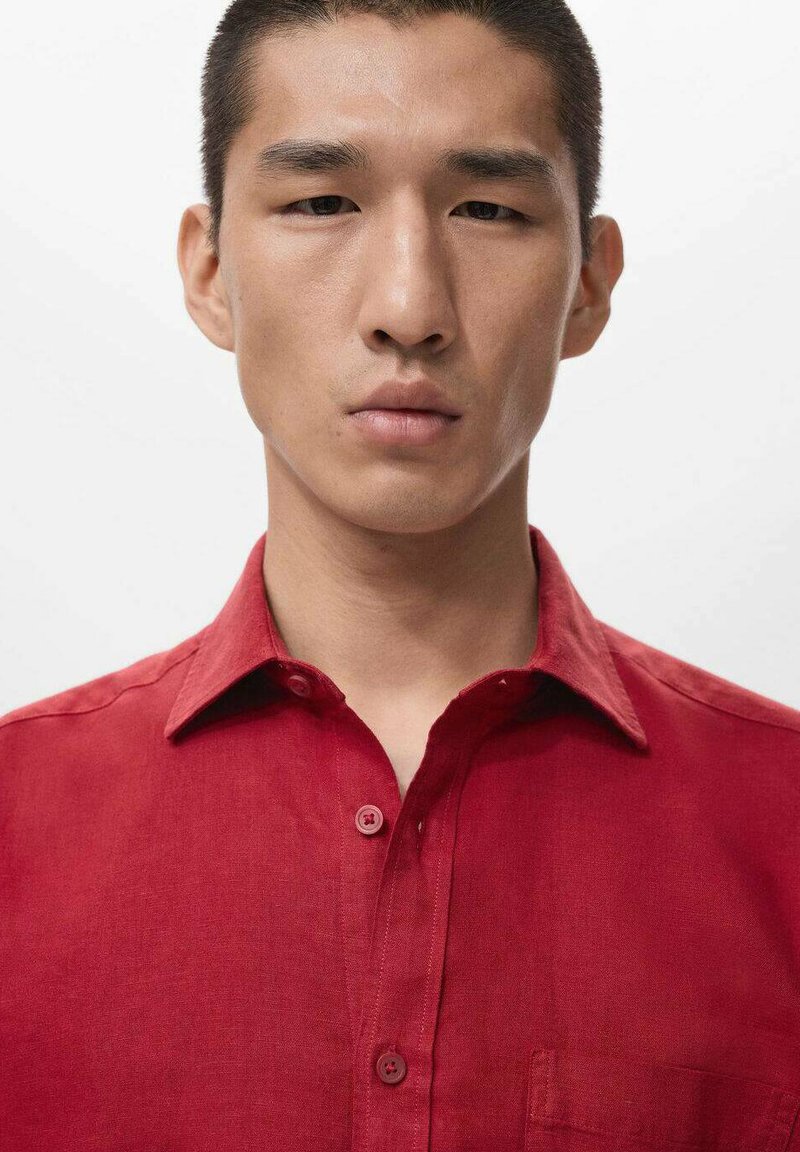 Rotes Leinenhemd mit Knopfleiste, klassischem Kragen, einer Brusttasche und passenden Knöpfen, mit einer glatten, leicht strukturierten Oberfläche.