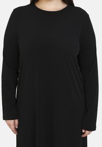 Schwarzes langärmliges Kleid mit Rundhalsauschnitt. Glatter Stoff, lockere Passform und keine sichtbaren Muster oder Akzente. Einfaches Design.