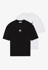 Två T-shirts: en svart med en vit spindel-logotyp, den andra vit med en svart skorpion-logotyp. Båda är kortärmade och med rund hals.