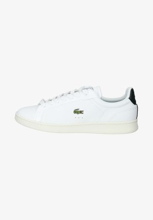 Baskets basses blanches avec lacets blancs, logo crocodile vert sur le côté et pièce noire au talon.