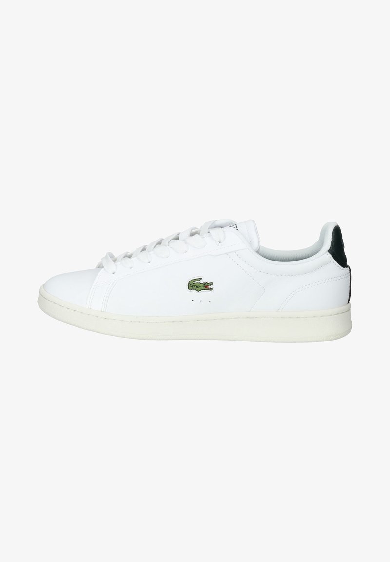 Baskets basses blanches avec lacets blancs, logo crocodile vert sur le côté et pièce noire au talon.