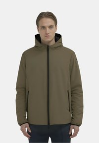 Giacca con zip verde oliva con cappuccio, dettagli neri e tasche laterali. Il tessuto appare liscio e leggermente strutturato.