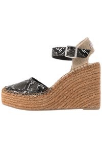 Klínové sandály s černo-bílým hadím vzorem, béžovým látkovým páskem kolem kotníku a platformou z tkaného juty. Pryžová podrážka pro lepší přilnavost.