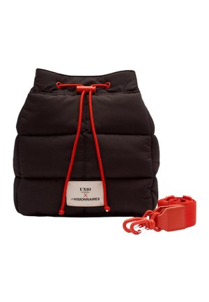 Sac matelassé noir à cordon avec des cordons rouges et une sangle rouge amovible, comportant une étiquette blanche avec du texte.