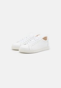 Weiße Leder-Sneaker mit einem niedrigen Design, runder Zehenpartie und flacher Gummisohle. Ausgestattet mit weißen Schnürsenkeln und minimalistischen Nähdetails.
